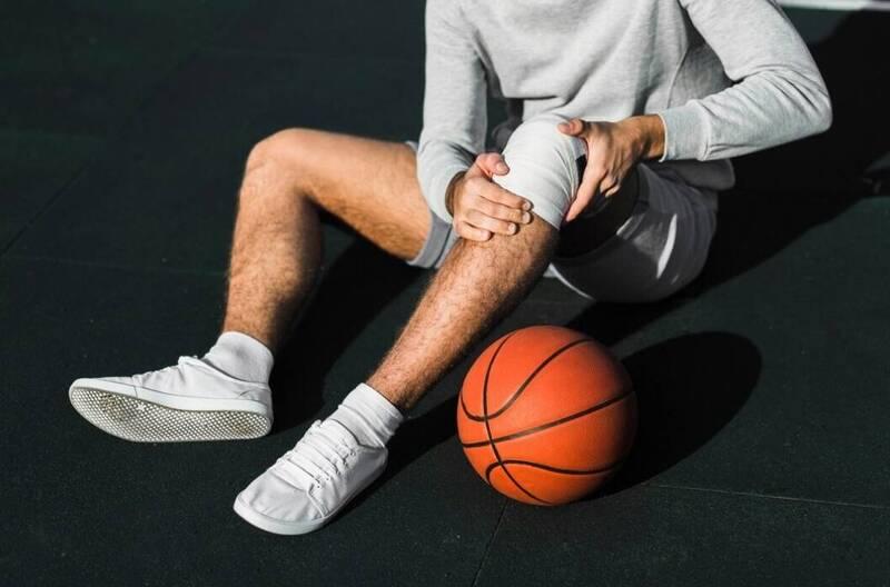 Basketball player landing with knee impact showing sports injury risk during high intensity movement