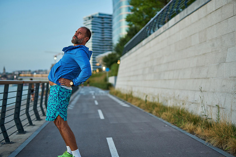 Athlete using sports lower back support tape to improve lumbar stability during running performance