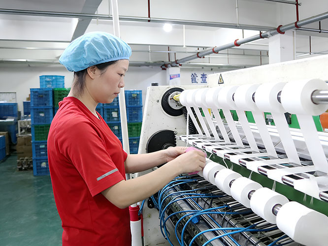 Workers inspecting kinesiology tape production machine in sports tape factory 