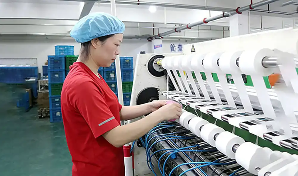Workers inspecting kinesiology tape production machine in sports tape factory